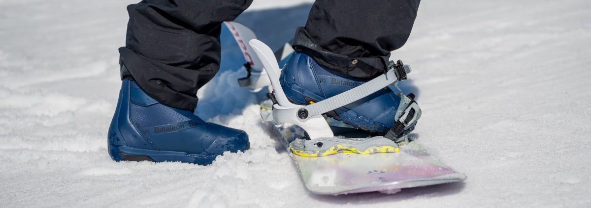 a women carrying a bataleon snowboard to display the bataleon women's snowboard bindings collection