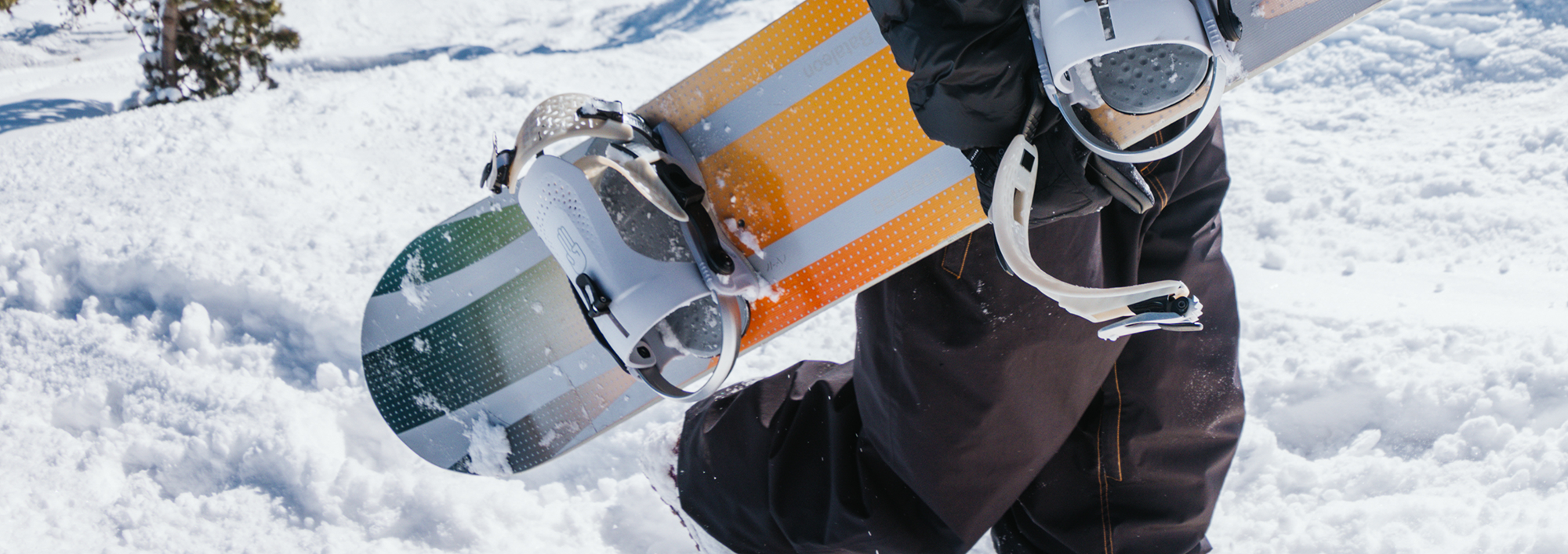 a women carrying a bataleon snowboard to display the bataleon women's snowboard bindings collection